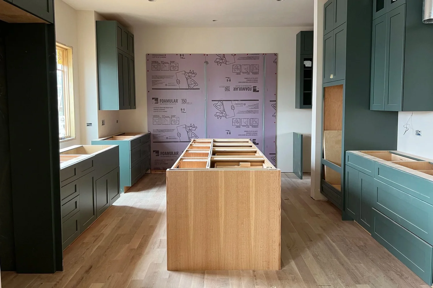 Kitchen cabinetry installation in progress with island and green cabinets